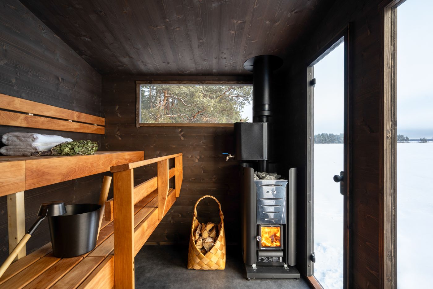 Authentic wood-burning sauna with Harvia stove and löyly bucket, vihta and towel on ice lake in Finland now available on the lakeside in Anières for hot sauna and winter swimming.